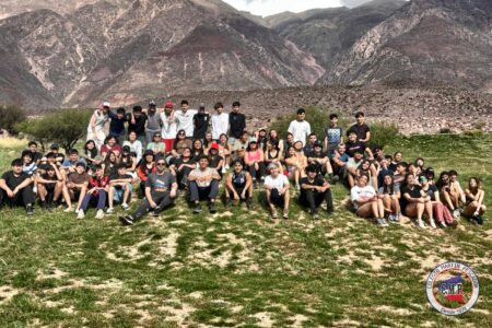 Estudiantes de 4.º y 5.º año en grupo sobre el pasto, con los cerros de la Quebrada de Humahuaca de fondo